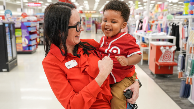 Store Director Tammy holds a giggling Azai, who is wearing a red and khaki team member outfit.