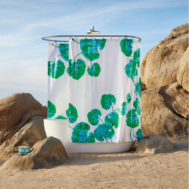 A shower displaying a curtain and towels with a floral motif against a desert background.