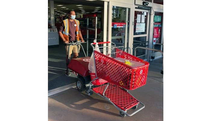 Jodi, wearing a mask and safety vest, pushes a Target cart through the entrance door.