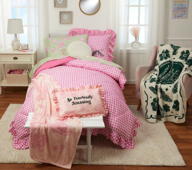 Twin sized green sheets, pink comforter, and pink decor pillow with “Be Fearlessly Amazing’ design.