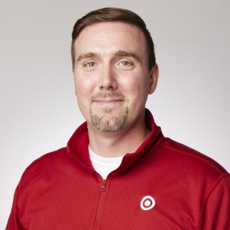 Rick W., smiling warmly and wearing a red Target-branded jacket.