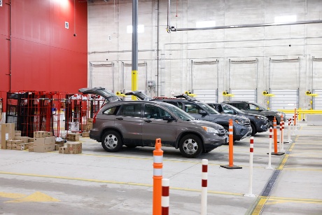Four vehicles lined up in a row with their back doors open prepare to receive guest orders.