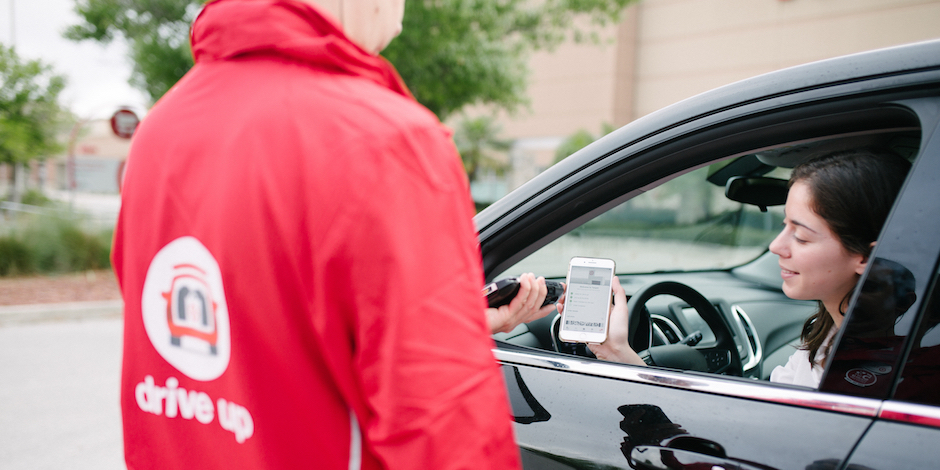 a man in a red sweatshirt holding a phone and a woman in a car