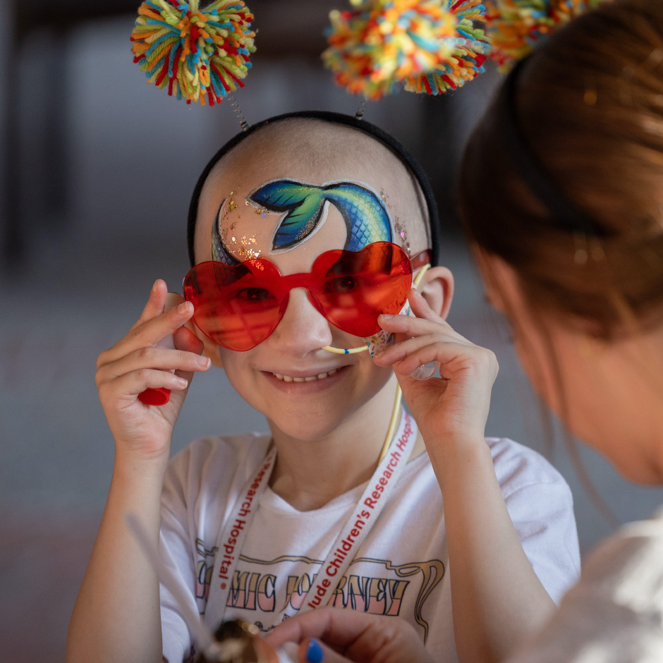 St. Jude patient Cypress smiles in face paint and colorful glasses.