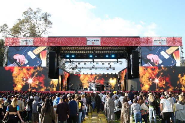 a crowd of people in front of a stage with a large screen