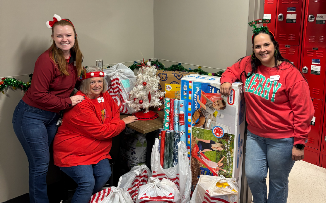 Three Target team members stand next to donations for the Great Giftogether.