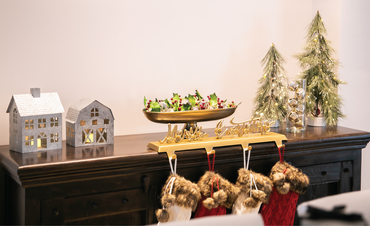 A table is decorated with a stocking holder, lighted trees and tin house and barn lanterns