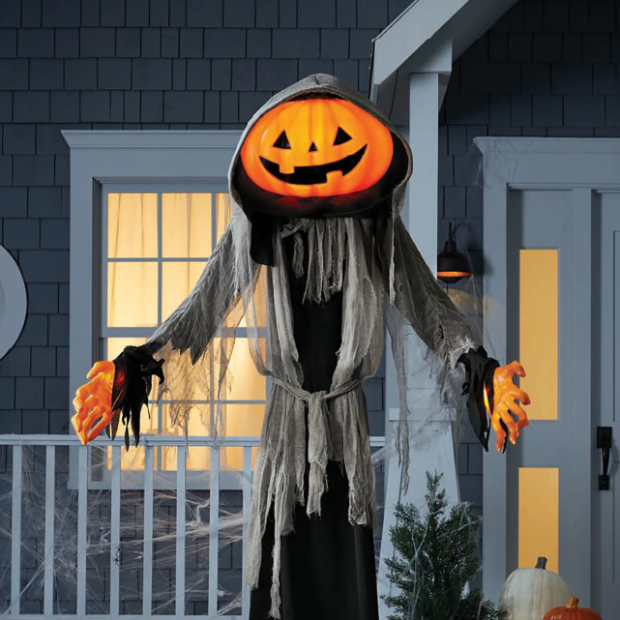 A grinning Lewis the Halloween Ghoul stands in front of a house.