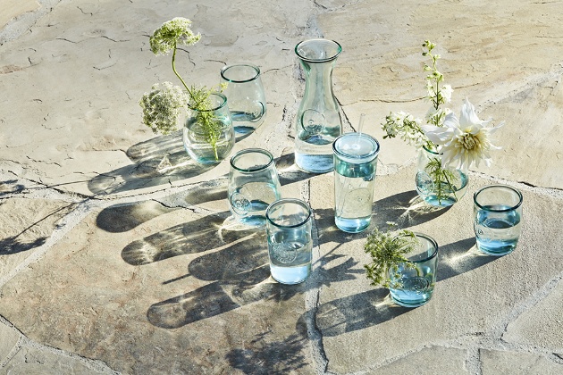 a group of glass vases sit on a stone surface