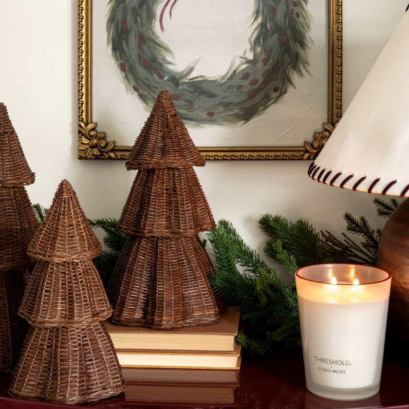 two miniature wicker Christmas trees and a candle