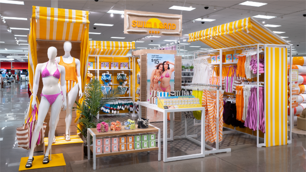 Target’s summer apparel and accessories area featuring mannequins in swimsuits, summer clothes and products in a yellow and white cabana-striped display area.