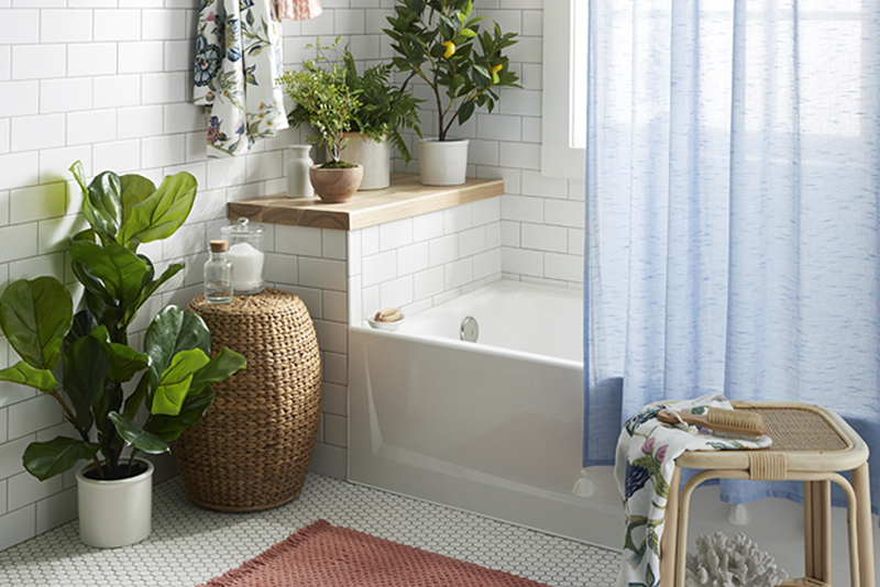 A bathroom brimming with faux greenery and airy blue curtain