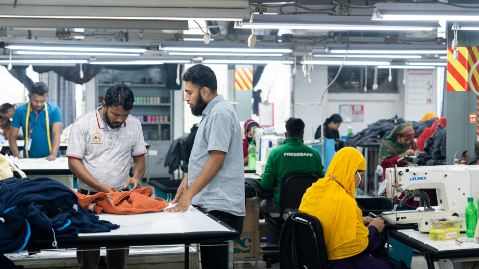 A workspace where people are handling garments and working with sewing machines