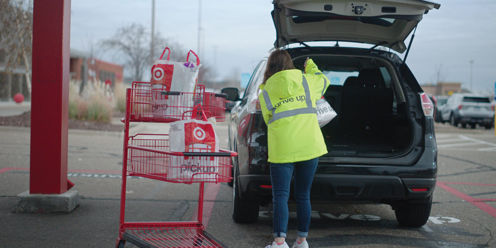 a person in a yellow jacket loading a car with a shopping cart