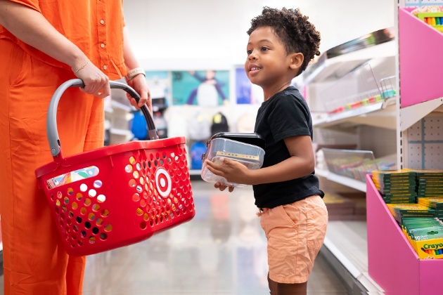 A child stands next to a Target guest holding a shopping basket.