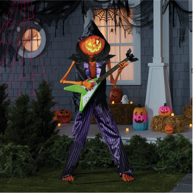 The Pumpkin Rocker Billy ghoul holding a green guitar standing in front of a house.