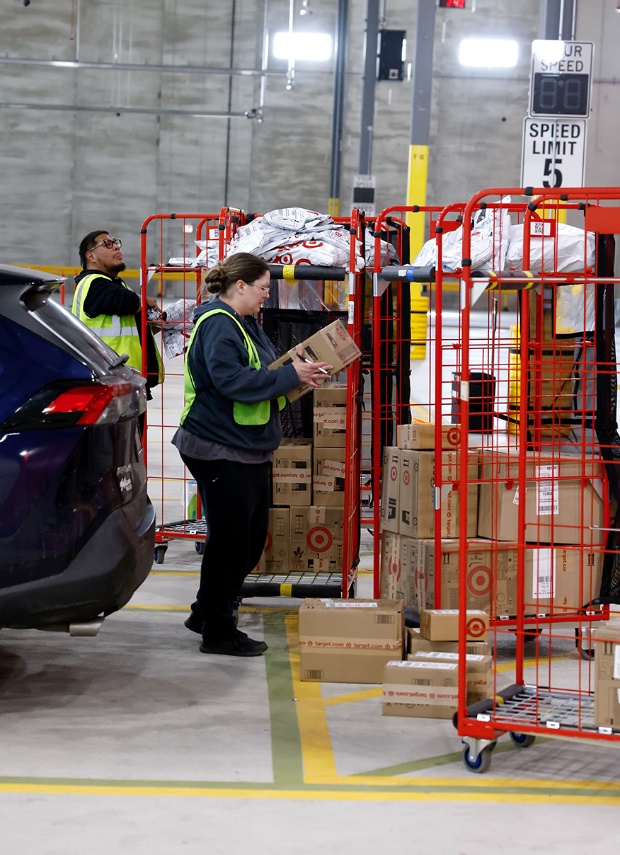 Two drivers stand in front of racks of guest orders to place in their vehicles.