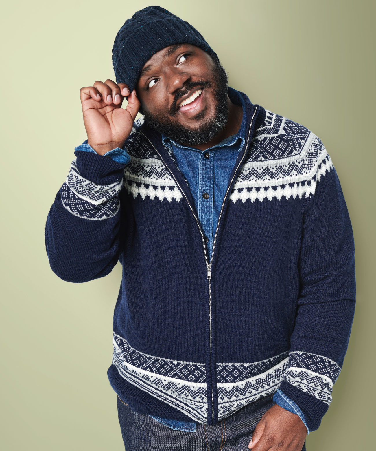 black man with beard wearing navy blue hat, blue zip-up sweater and denim shirt