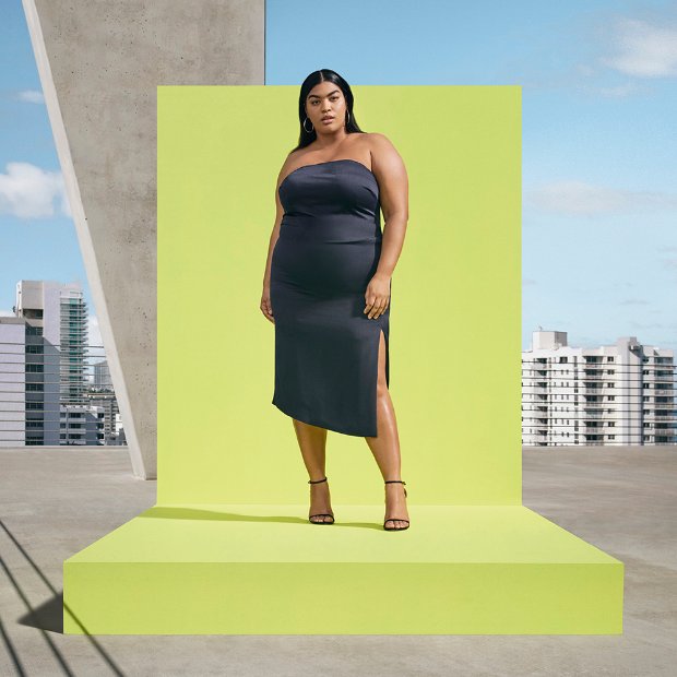 a woman in a dress standing in front of a large green wall