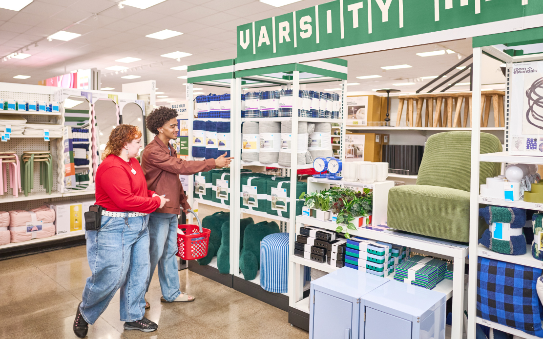 A Target team member and a college student walking in the Varsity Hall section of a Target store.