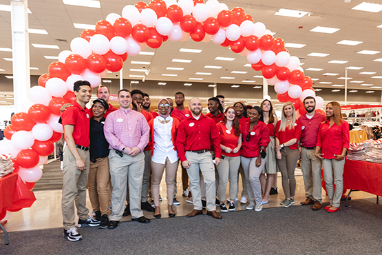 Mike and team standing under a balloon arch