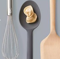 Overhead photo of a whisk, serving spoon and wooden spoon