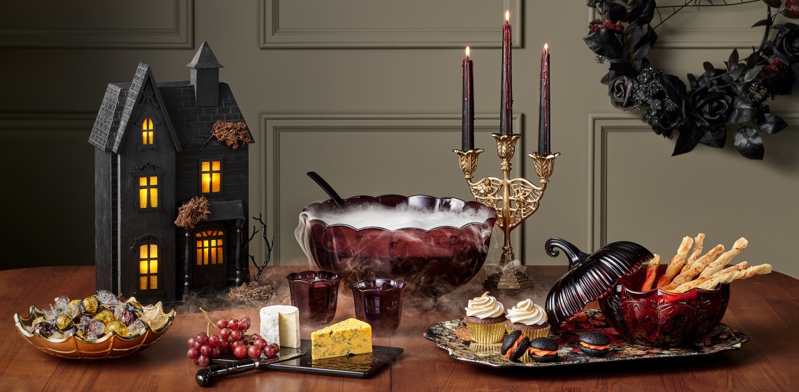 A table set with Halloween items including a gold candelabra and trays with food.