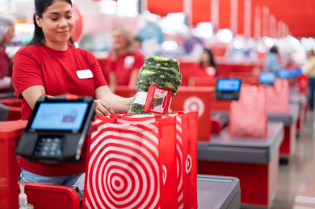 A Target team member stands at checkout and places a holiday blanket in a Target bag.