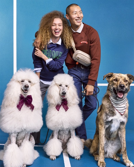 Two models pose with three dogs wearing the Cuddle Collab collection.