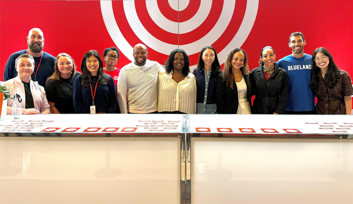 A group of 12 people pose in front of a red and white Target bullseye backdrop.