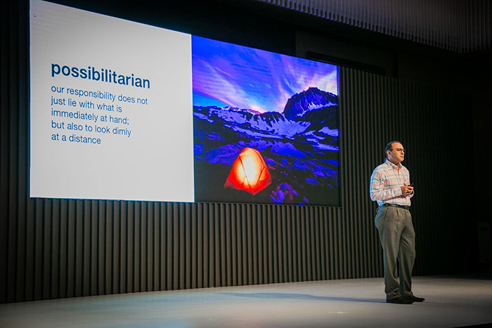 a man standing in front of a large screen