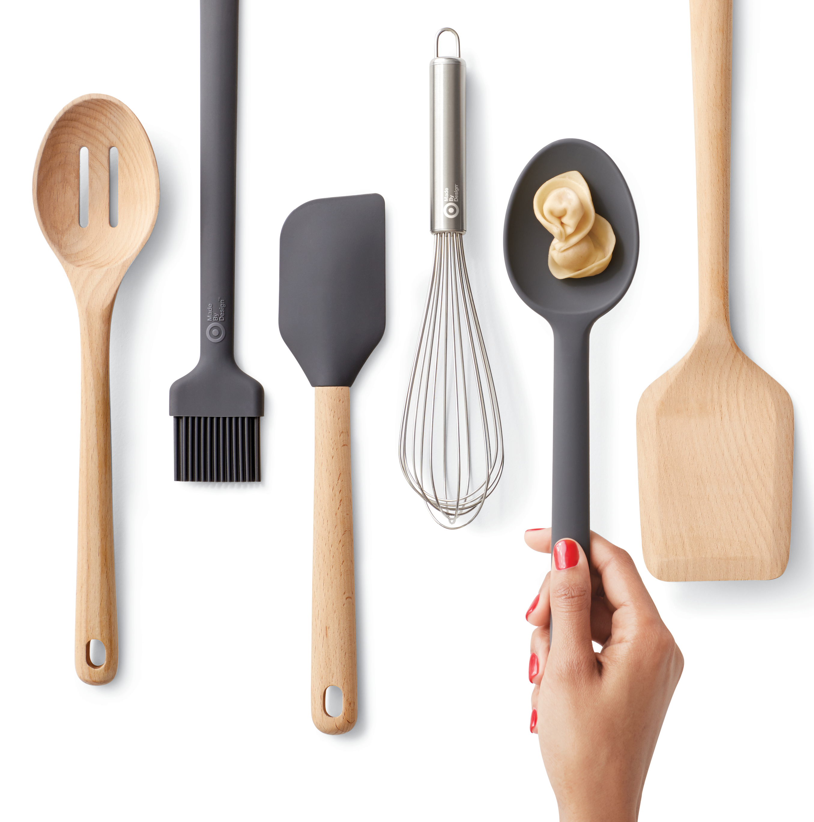 A mix of plastic and wooden kitchen utensils, including slotted and regular spoons, basting brush, spatula and whisk