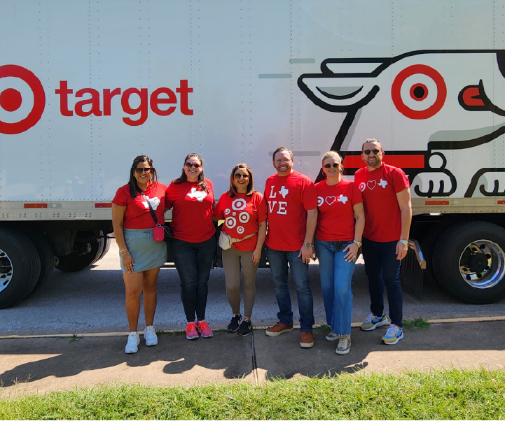 a group of people in red shirts standing in front of a truck