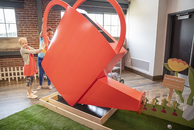 a person and a child standing next to a red sculpture