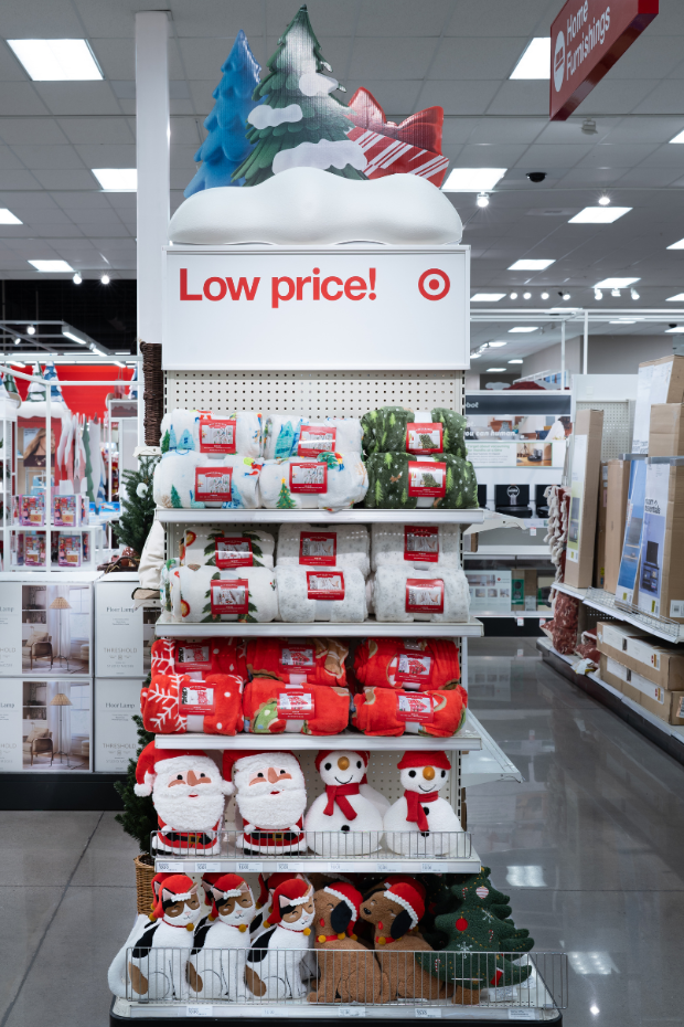 An endcap that says “Low price” is full of plush  holiday-themed blankets and pillows.