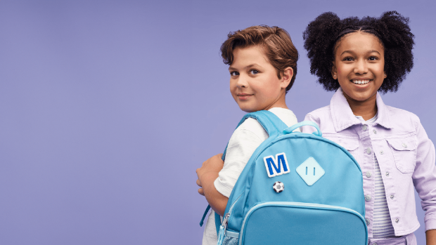 Two children smile wearing items from Target, including a backpack.