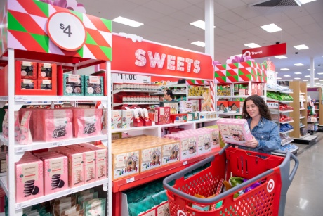 A guest pushing a red cart shops for holiday treats. Signs read Sweets and $4.