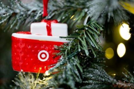 A red Target basket ornament is hanging on a Christmas tree.