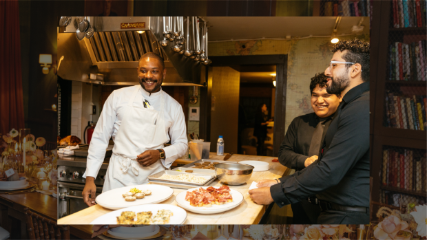 A smiling Chef Mitchell prepares food dishes alongside two people wearing all black professional attire.