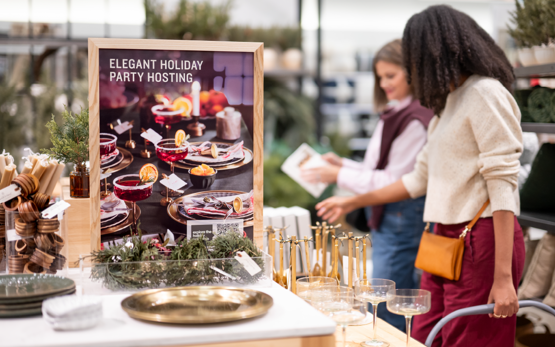 Two guests shop a table of holiday party hosting items.