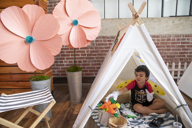 a kid sitting in a chair under an umbrella