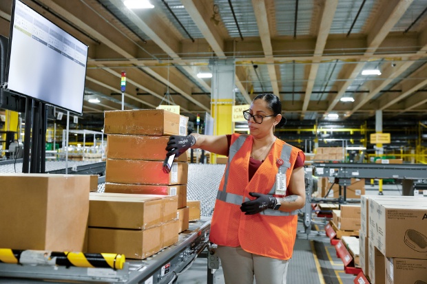 A team member wearing a vest scans a boxed package.