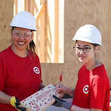 Two Target volunteers smile wearing hardhats.