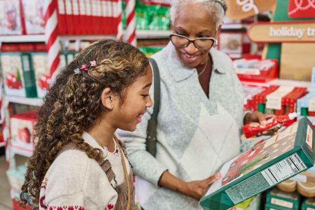 Close-up of a shopper holding a gingerbread kit in a decorated holiday treats aisle.