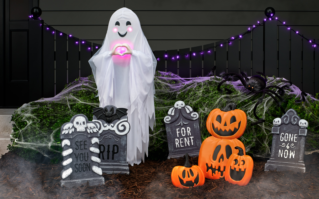 An outdoor Halloween display with a ghost, gravestones and pumpkin decorations.