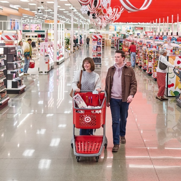 Two people push a shopping cart down a wide store aisle