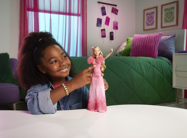 A girl playing with a doll that resembles the Wicked character Glinda.