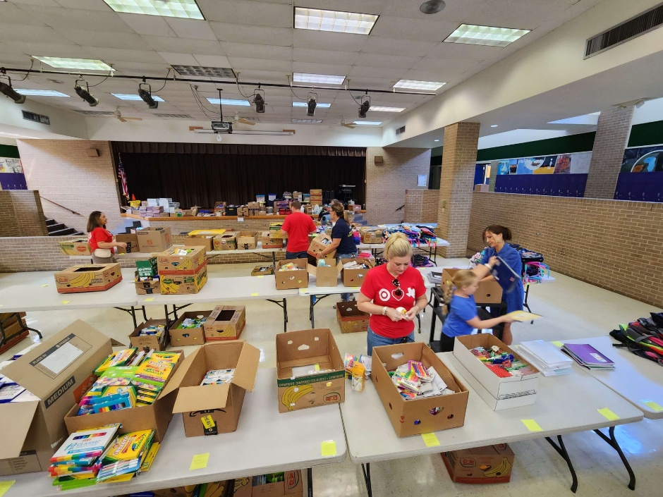 A group of Target team members sort school supplies and other essentials in a large room.