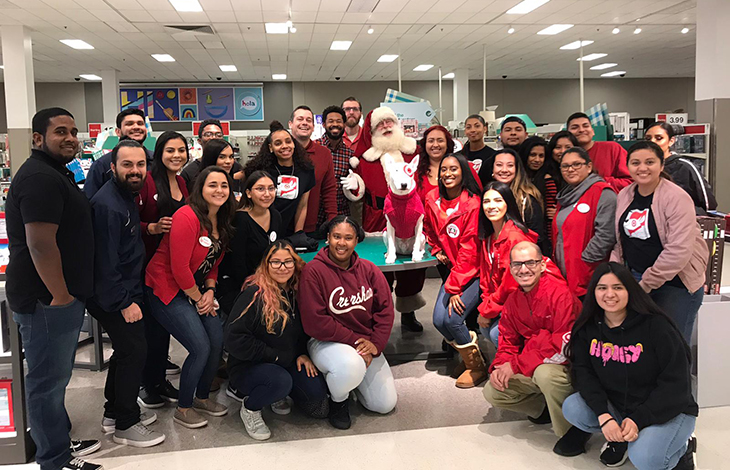 A large group of team members pose with Bullseye and Santa