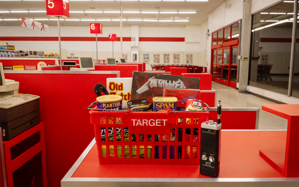 A campaign photo features the checkout counter at a 1987 Target store with a retro Target basket filled with popular 80s products and brands. A Walkie Talkie sits on the counter next to the basket.